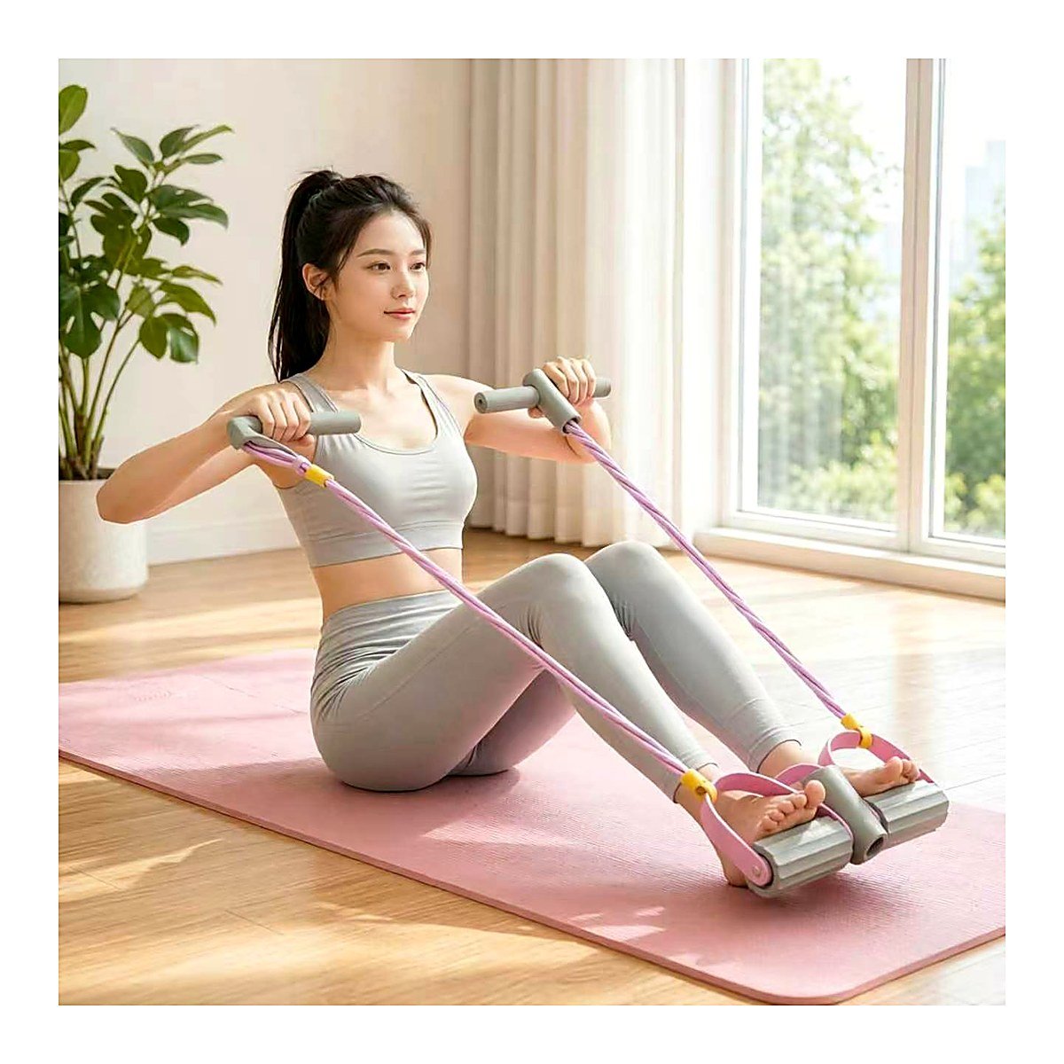 Woman using a grey and pink pedal resistance band for a seated row workout